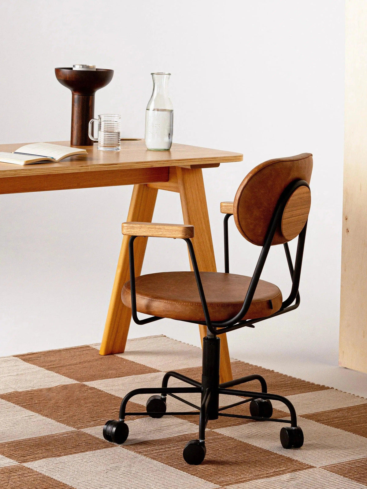 Detalhe do tapete Chroma cru e camelo sob cadeira giratória de madeira junto à mesa de trabalho.