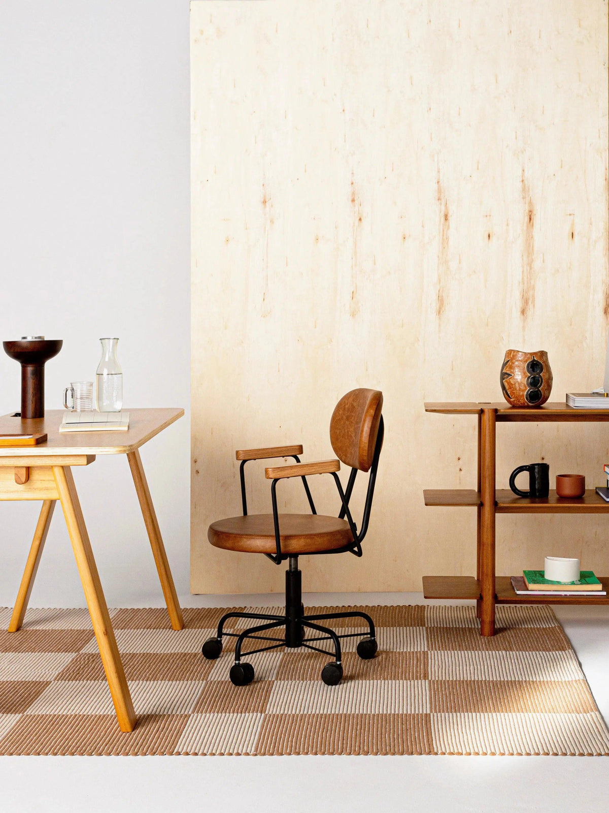 Tapete Chroma quadriculado cru e camelo em escritório com mesa de madeira e cadeira rodinhas.