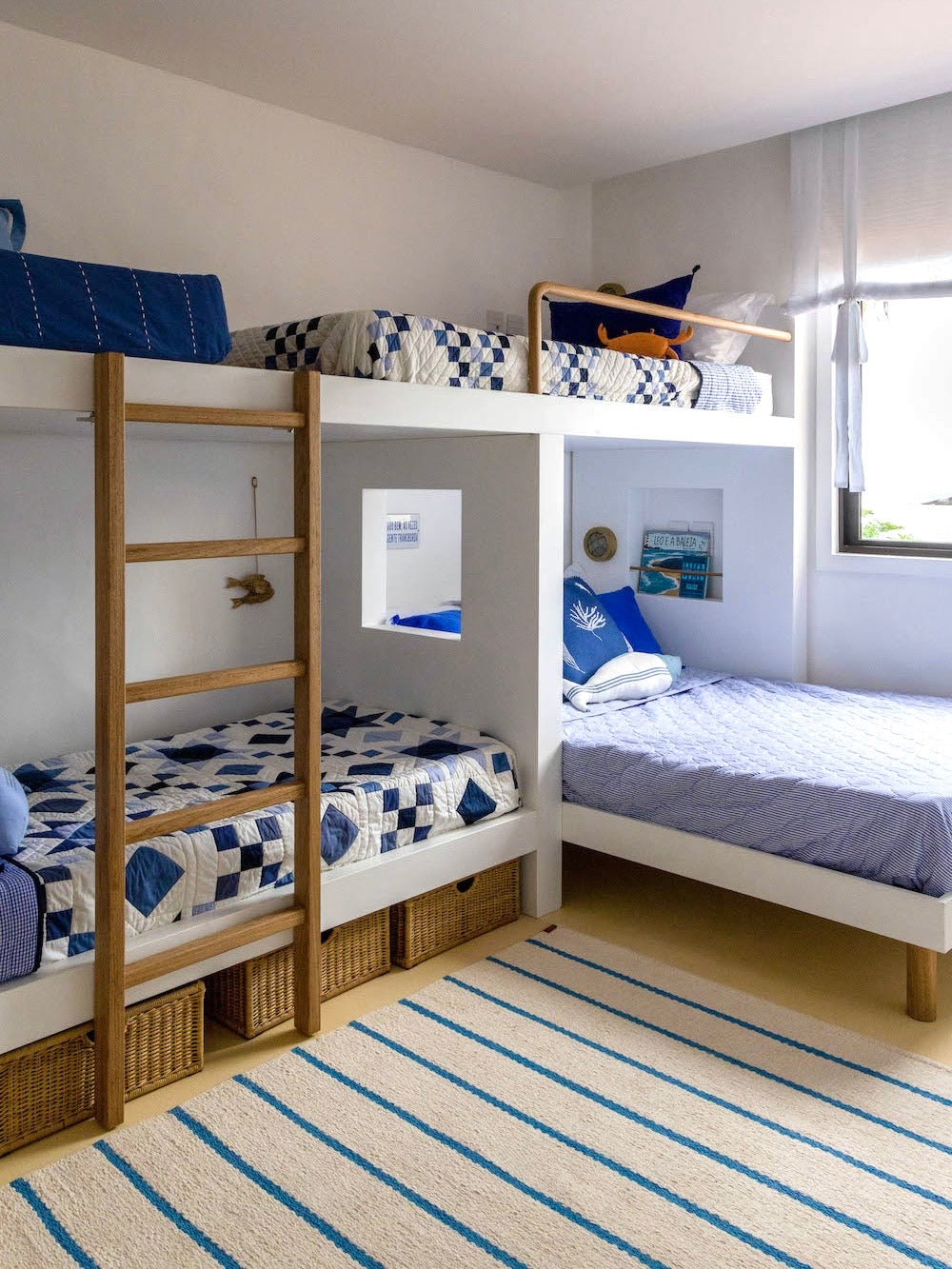 Tapete Pontal com listras azuis em quarto com beliche e cama junto à janela.
