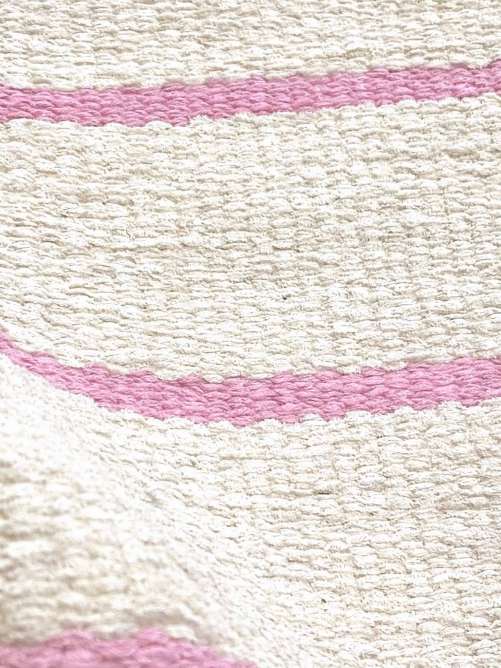 Detalhe da textura do Tapete Pontal de fundo cru com listras rosas.