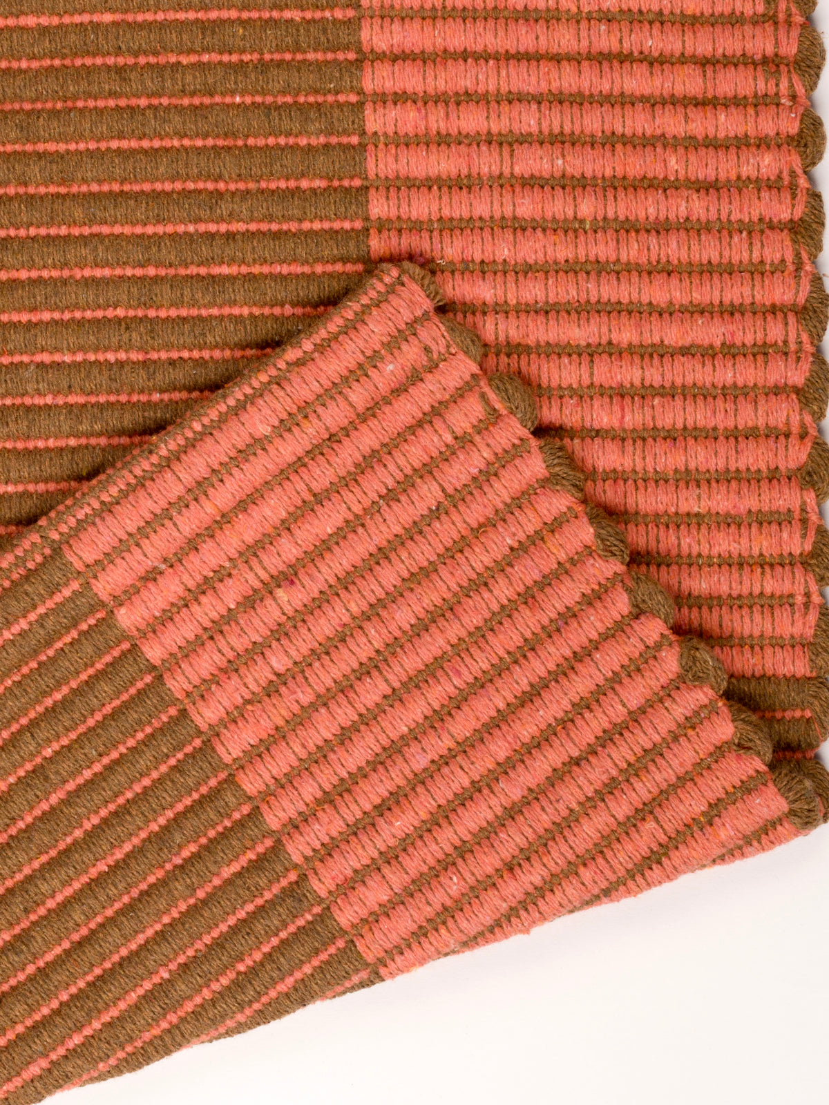 Detalhe do padrão quadriculado laranja e camelo do tapete Chroma