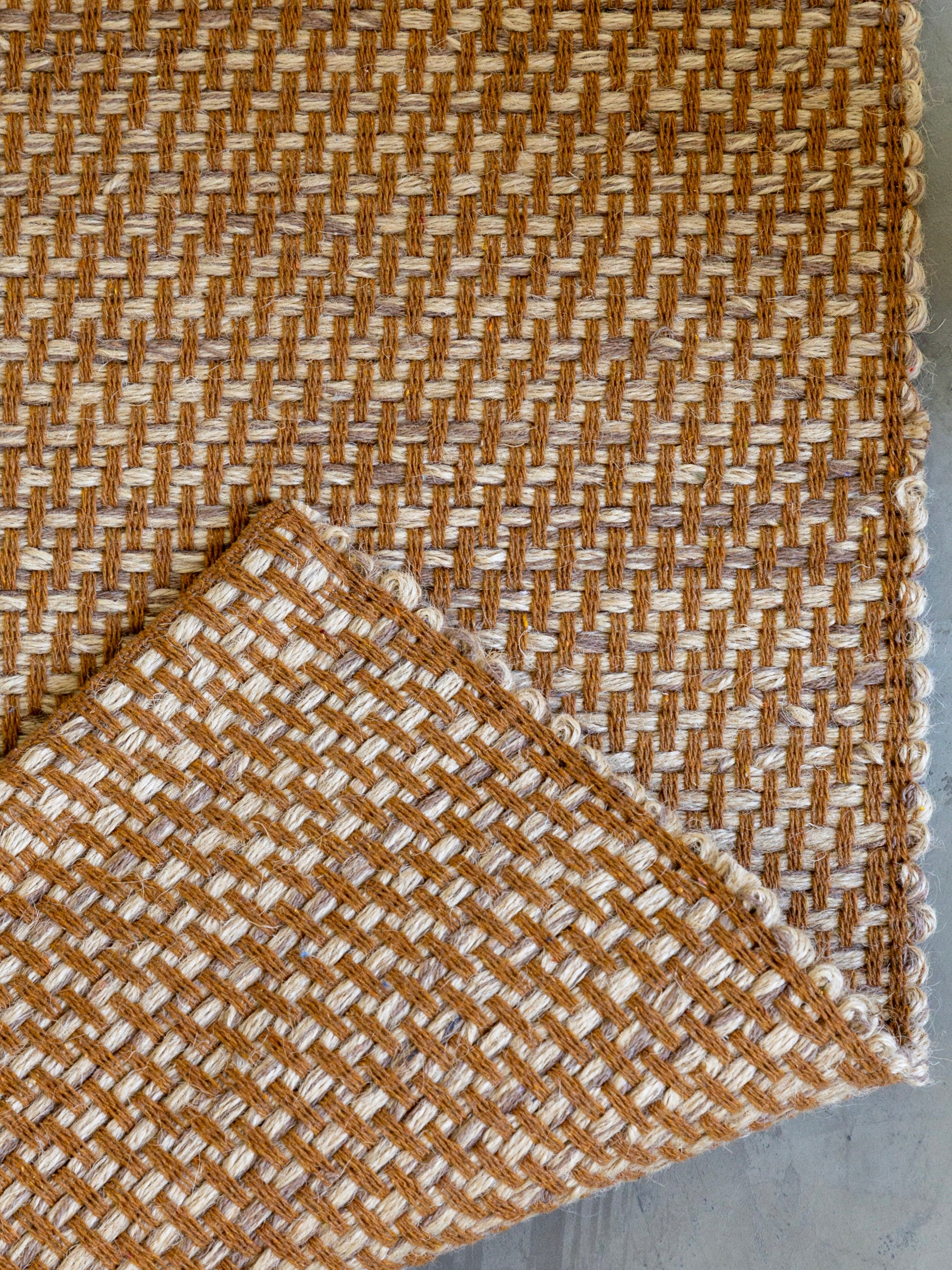 Detalhe do canto do Tapete Milah camelo em juta e algodão.