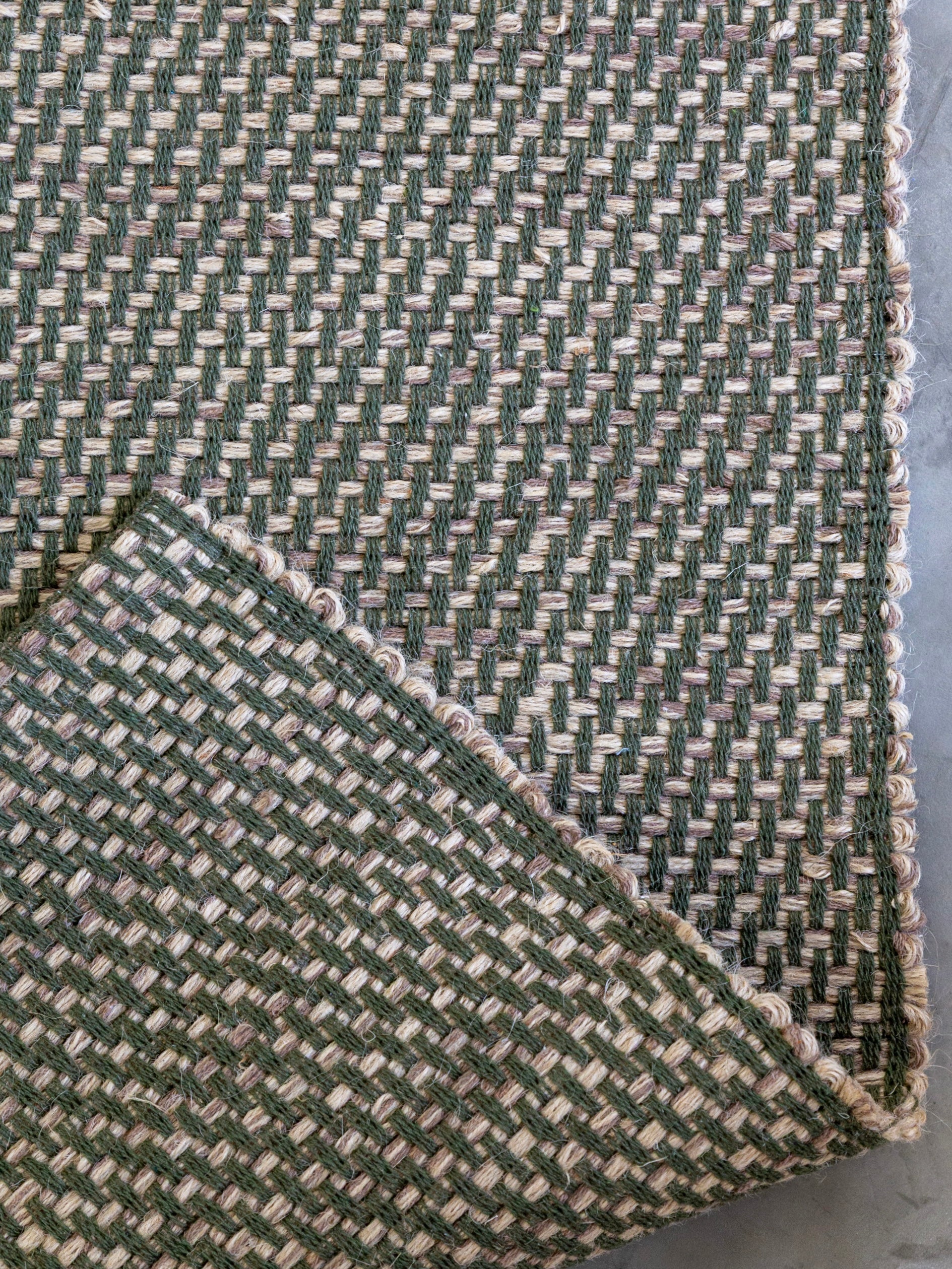 Detalhe do canto do Tapete Milah verde-oliva em juta e algodão.