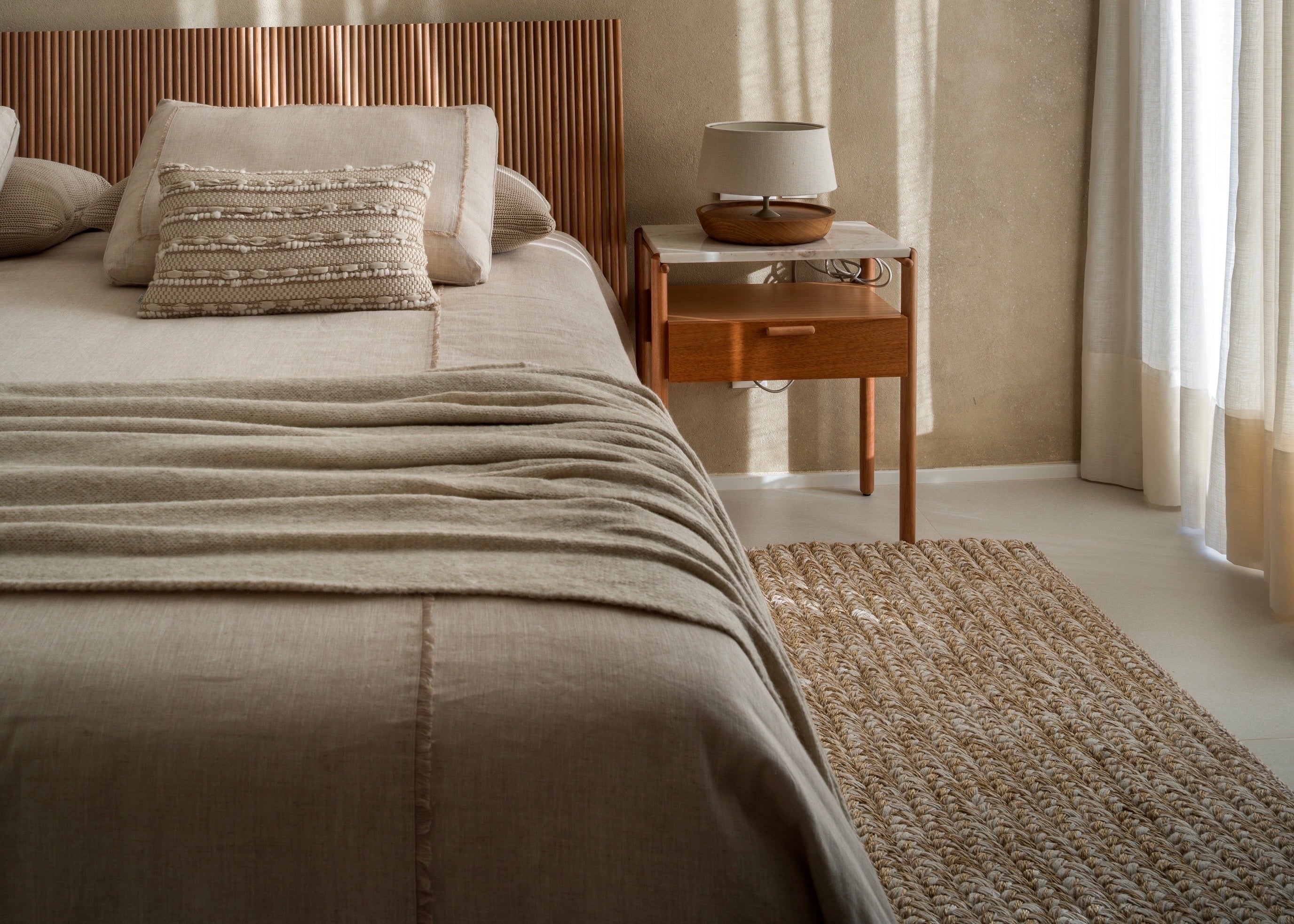 Como usar tapete no quarto de casal com passadeira de fibra natural ao lado da cama, criando conforto ao caminhar e uma composição acolhedora.